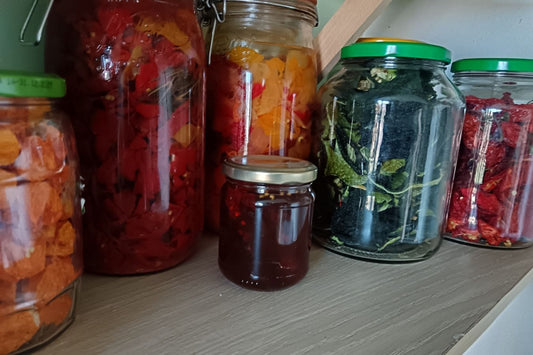 Bocaux en verre de différentes tailles remplis de piments séchés, herbes et sauces maison sur une étagère - bar à piment Pimento Momentum
